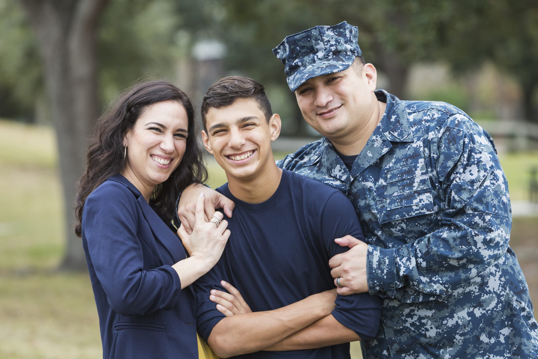 A mother, a father in a military uniform and their teen son smile for a picture.