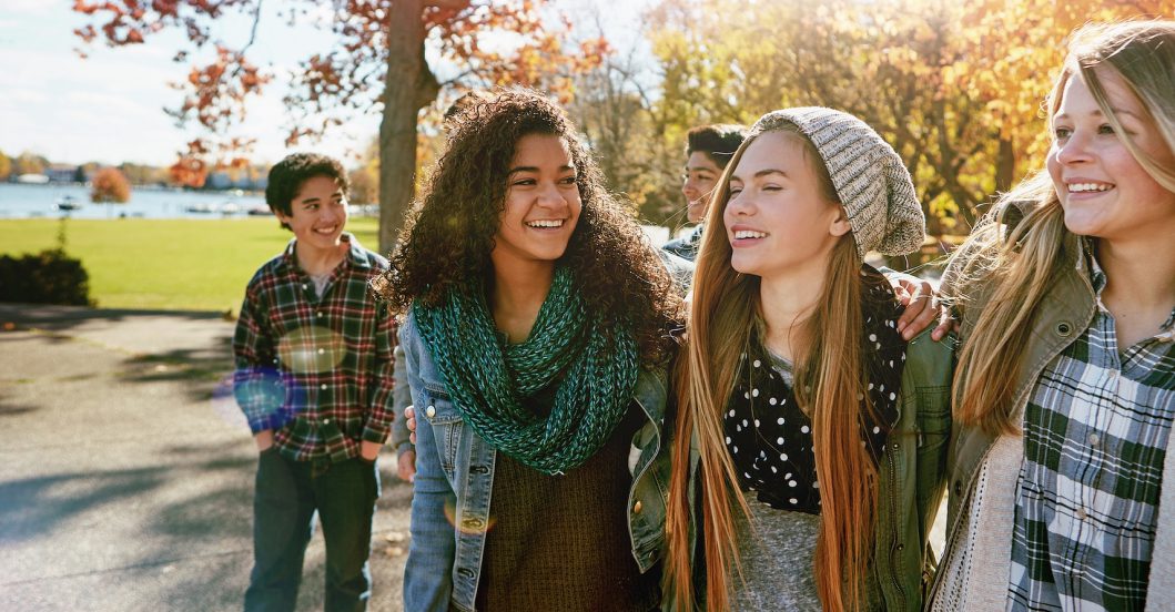 Three young women stand together, smiling and enjoying their time outdoors.