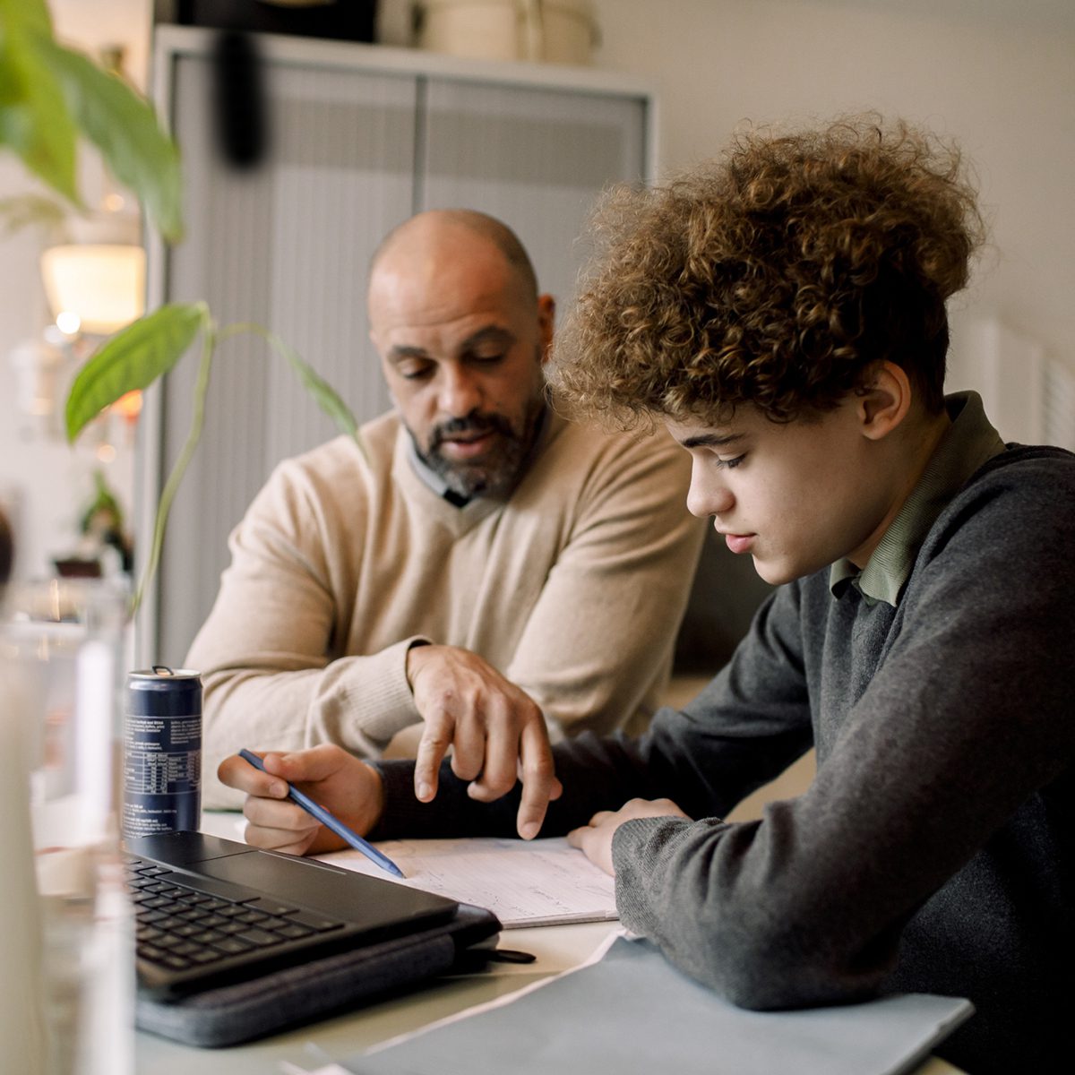 A father helps his teenage son work on his homework assignment