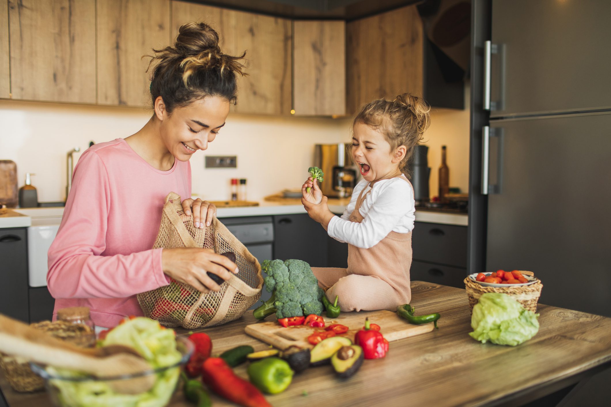 Mother and daughter put away vegetables and healthy foods together.
