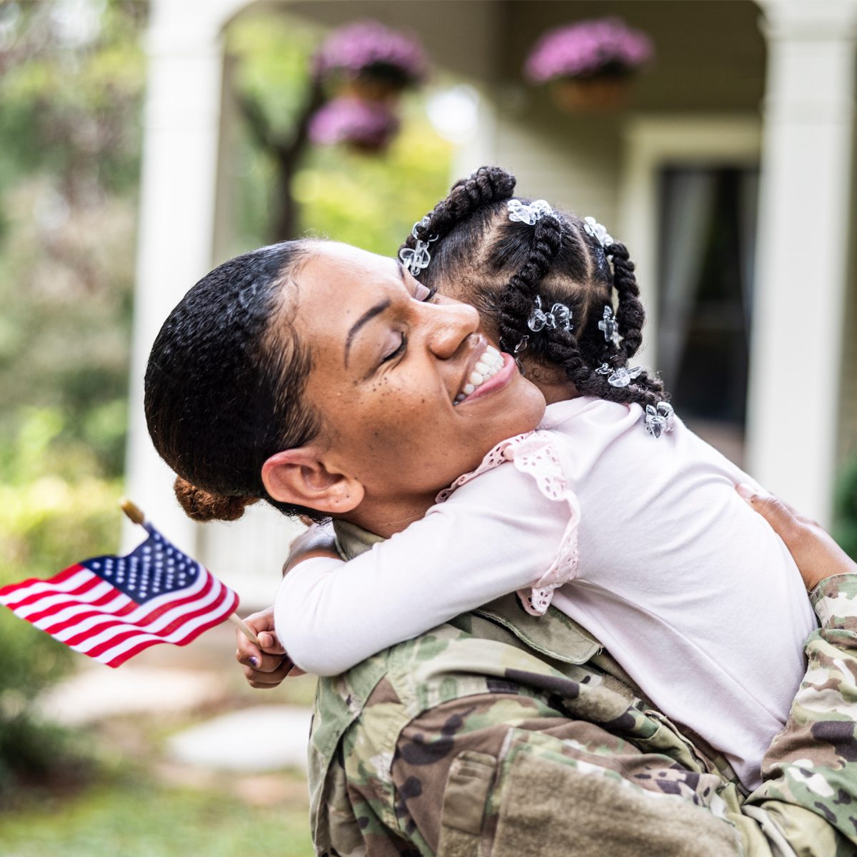 woman smiling and holding her child who has an american flag in hand