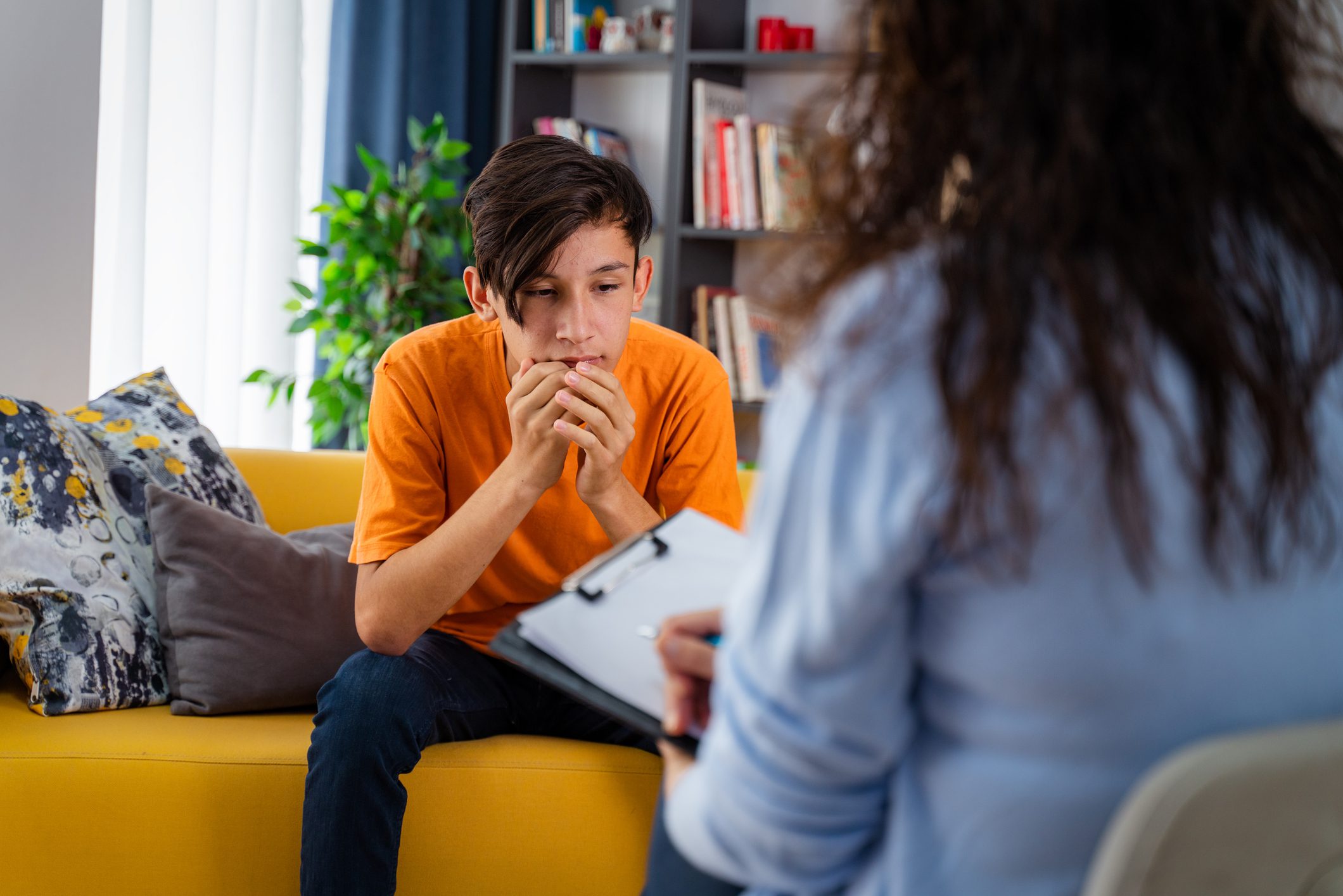 Female psychologist provides emotional regulation counseling to teenage boy.