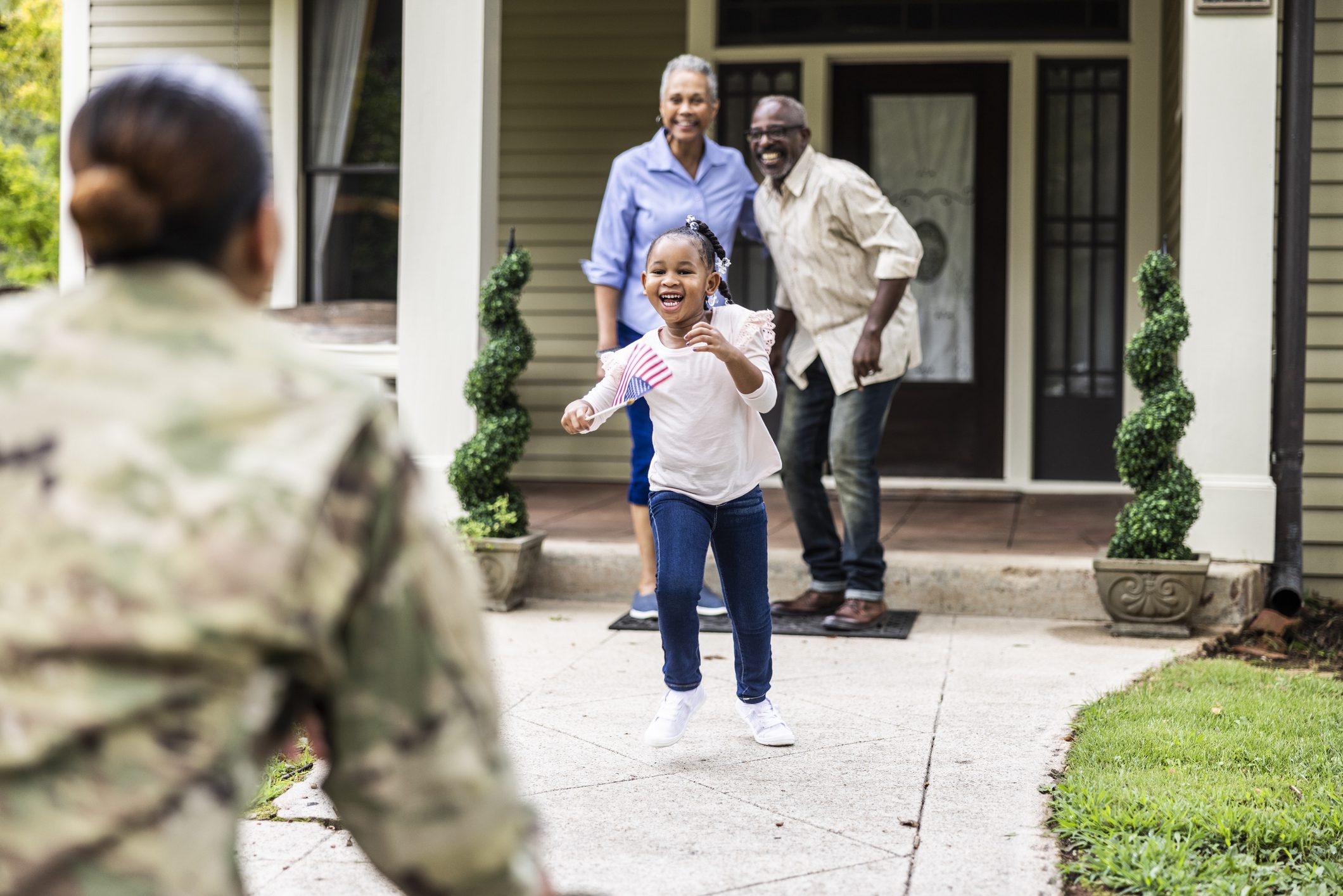 Multi generational family welcoming home female U.S. soldier in uniform in front of home Military Families Resources
